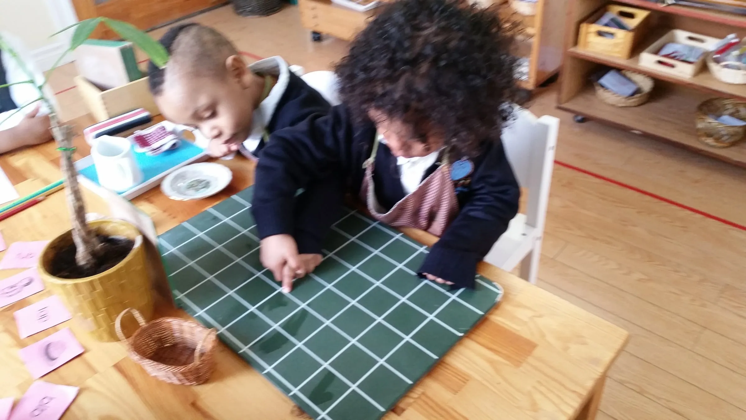 Two children working together at a table on the Montessori hundred board