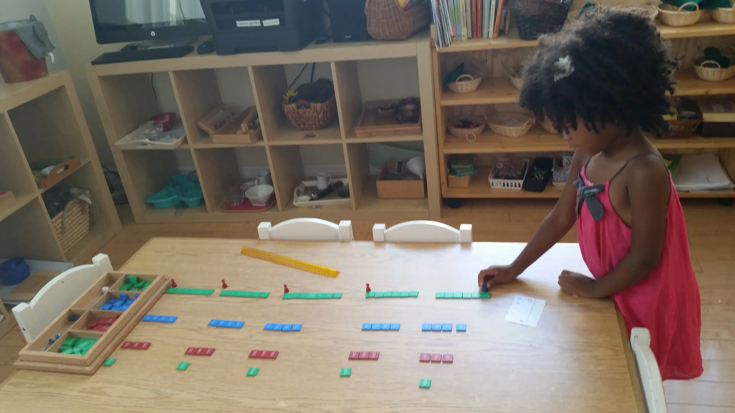 A child laying out number rods and bead bars across a long table